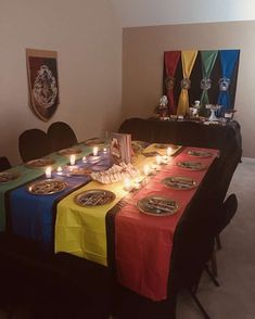 a long table with plates and candles on it in the middle of a dining room