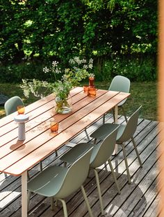 a wooden table sitting on top of a wooden deck next to flowers and potted plants