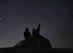 two people are sitting on the back of a truck at night with stars in the sky