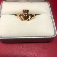 a gold ring in a box on a red surface