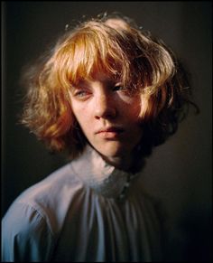 a young boy with blonde hair is looking at the camera