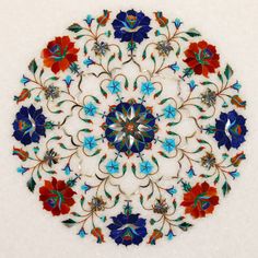 an intricately designed glass plate with red, blue and green flowers in the center