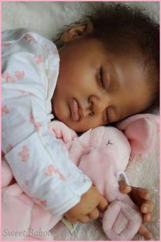 a baby sleeping on top of a pink stuffed animal