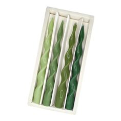 four green and white candles in a box