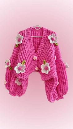 a pink cardigan with flowers on the front and back, sitting against a pink background