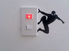 a white light switch with a spiderman sticker on the wall next to it