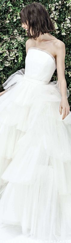 a woman in a white dress is sitting on a bench and looking down at the ground