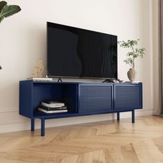 a blue tv stand with a plant on top of it in front of a white wall