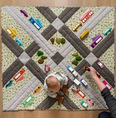 an overhead view of a baby playing with toy cars on a quilted floor mat