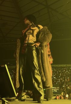 a man standing on top of a stage next to a woman in a fur coat