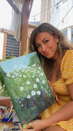 a woman sitting on the ground holding a painting