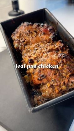 a pan filled with meat sitting on top of a counter next to a knife and fork