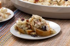 two plates with food on them sitting next to a casserole dish filled with stuffing