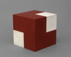 a red and white block sitting on top of a gray floor next to a wall