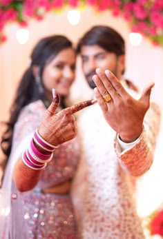 the bride and groom are holding their hands up to show off their wedding rings in front of them