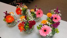 several vases filled with different colored flowers on a white tablecloth covered table top