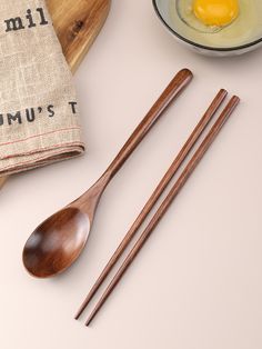 two wooden spoons, one with an egg and the other with chopsticks