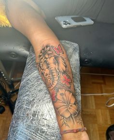 an elephant and flowers tattoo on the arm