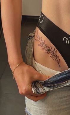 a woman with a tattoo on her stomach holding onto a pair of jeans that are open