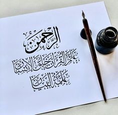 an arabic calligraphy is displayed on a sheet of paper next to a fountain pen