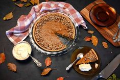 a pie sitting on top of a table next to a knife and bowl of whipped cream