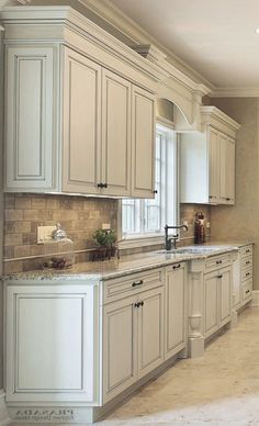 a kitchen with white cabinets and marble counter tops