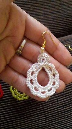 a person is holding some white crochet earrings in their hand and they are all different colors