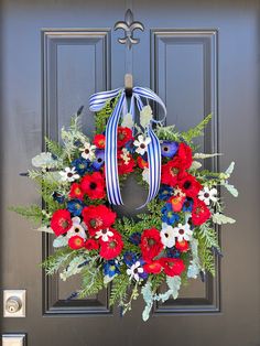 a wreath with red, white and blue flowers is hanging on the front door handle