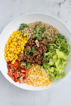 a white bowl filled with different types of food on top of a marble countertop