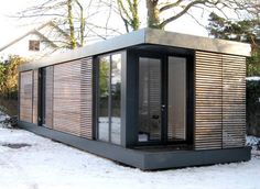 a small wooden structure in the snow with sliding doors on it's sides and windows