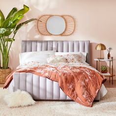 a bedroom with pink walls and white bedding in the corner, along with a plant