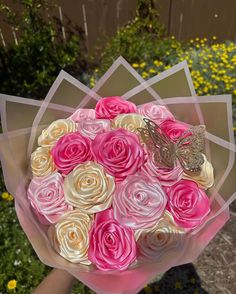 a bouquet of pink and white roses in someone's hand with a butterfly on it