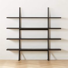 a black shelf with several shelves on it and a wooden floor in front of the wall