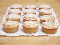 a table topped with lots of cupcakes covered in powdered sugar on top of paper