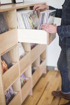 a man is holding a record player in his hand while standing next to a book shelf