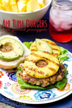 a plate topped with a burger next to a bowl of fruit