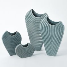 three grey vases sitting next to each other on a white surface with wavy lines