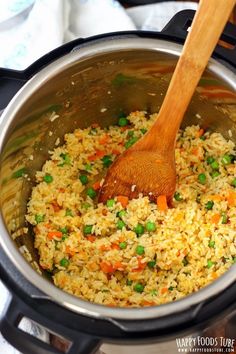 a wooden spoon in a pot filled with rice and vegetables