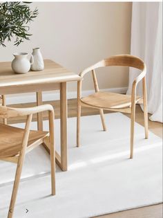 a table with two chairs and a vase on it in front of a white rug