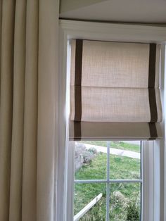 an open window with the blinds pulled back and striped valance on it's side