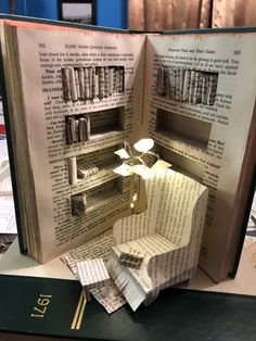 an open book with pages cut out to look like a lamp and bookshelf