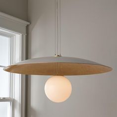 a light fixture hanging from the ceiling in a room with white walls and windows behind it