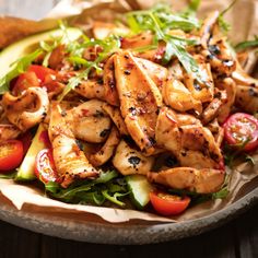 a plate filled with chicken and veggies on top of a wooden table