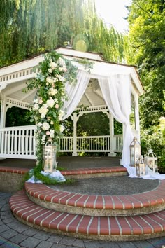 an outdoor gazebo decorated with flowers and greenery