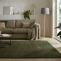 a living room with a couch, table and lamp on the floor in front of a large window