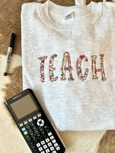 You will absolutely LOVE this this fun sweatshirt for your favorite educator! This beautiful embroidered appliqué sweatshirt will keep you cozy, warm and stylish for all of your busy days at school!💛  Fabric options are either pink floral or blue floral as shown above, be sure to include which you would like! Embroidered Applique Sweatshirt, Embroidered School Sweatshirt, Fall School Tops With Embroidered Logo, Cotton Sweatshirt With Machine Embroidery For College, School Spirit Embroidered Cotton Sweatshirt, Cotton Sweatshirt With School Spirit Embroidery, Embroidered Cotton Sweatshirt For School Spirit, Fall School Tops With Embroidery, Cotton Embroidered Sweatshirt For School Spirit