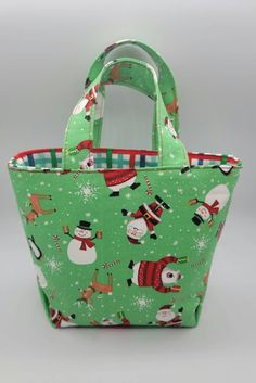 a green christmas shopping bag with santa claus and snowmen on the front, sitting against a white background