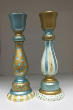 two blue and gold candlesticks sitting next to each other on a white surface