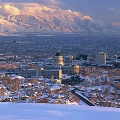 a city with mountains in the background and snow covered ground on the foreground,