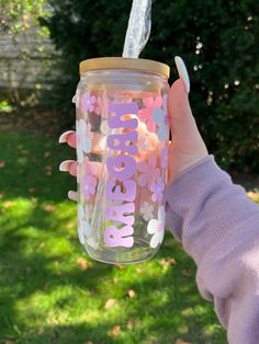 a person holding up a mason jar with flowers on it and the words baby in pink